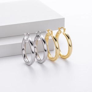Macro detail of chunky gold and silver S925 sterling silver hoop earrings on gray blocks