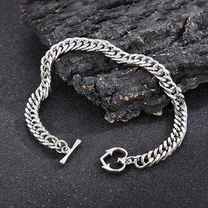 Détail du bracelet gourmette en acier argenté avec fermoir coeur sur fond de pierre noire