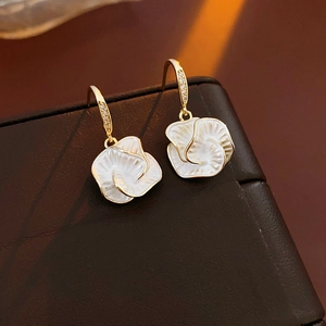 Macro view of vintage gold-plated flower earrings with shell petals and zircon hooks