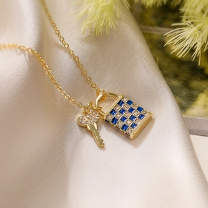 Macro view of 18K gold plated lock and key pendant necklace with blue checkered pattern