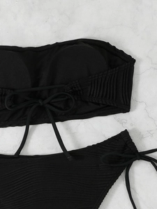 Detail of black bandeau bikini showing tie-back design and textured pleated fabric