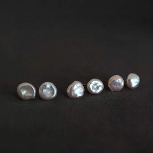 Three pairs of irregular baroque pearl stud earrings with natural luster on a dark background