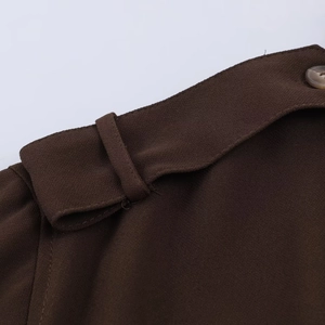 Détail du tissu tissé marron avec patte d'épaule boutonnée et bouton en bois