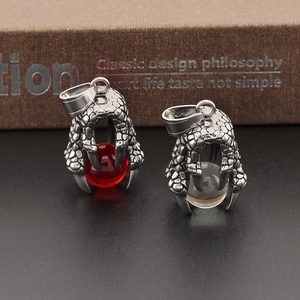 Macro shot of stainless steel dragon claw pendants with red and clear beads on vintage books