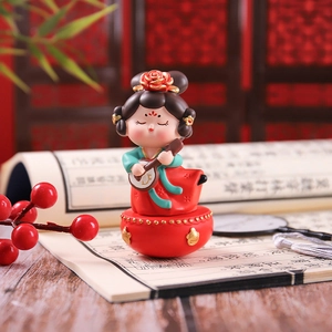 Detail of a Q-version ancient Chinese figurine in green and red dress holding an instrument