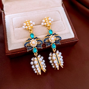 Detail of vintage bow earrings with pearls and emerald gems in a leather jewelry box