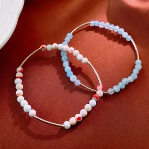 Elegant Aquamarine beaded bracelet set with stylish metallic tubes on a textured fabric