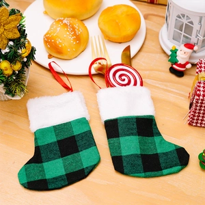 Mini green plaid Christmas stocking cutlery holder with white faux fur on wooden desk