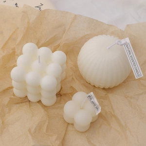 Minimalist white bubble cube and striped spherical soy wax scented candles on brown paper