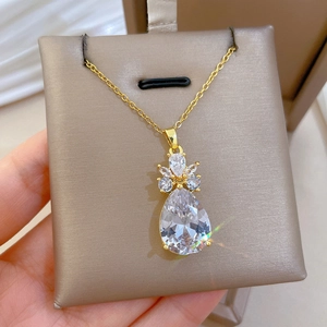 Détail d'un collier en titane doré avec cristal en goutte et motif de couronne