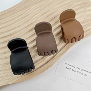 Three matte high ponytail shark clips in black and brown on a wooden tray