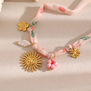 Detail of pink floral ribbon necklace with sun face pendant and baroque pearl