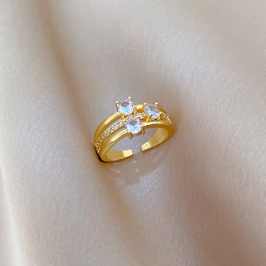 Detailed shot of gold-plated three-stone adjustable ring on silk fabric background