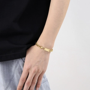 Macro view of golden stainless steel Cuban chain bracelet with rectangular blank tag