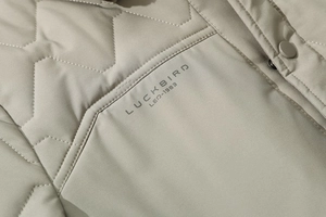 Detail of the light greyish-green quilted jacket with V-pattern stitching and snap button