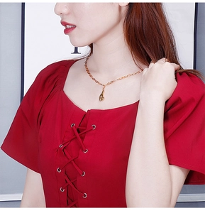 Gros plan d'un collier en titane doré avec pendentif geste de cœur porté par un mannequin