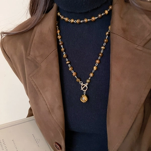 Collana di perle occhio di tigre con pendente rotondo e chiusura dorata su modella