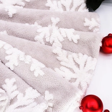 Detail of plush gray Christmas fabric with white snowflake patterns and festive red decor