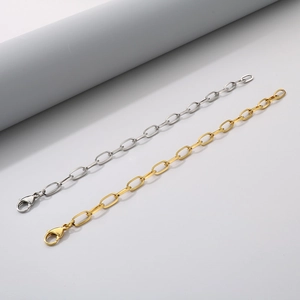 Detail of silver and gold stainless steel link bracelets with lobster clasps on a prop