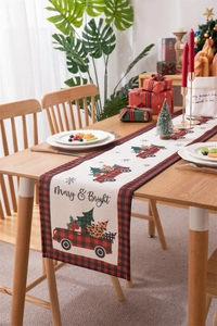 Christmas table runner with red truck and plaid border on festive wooden dining table