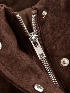 Macro shot of dark brown faux suede fabric featuring silver metal zipper and snap button