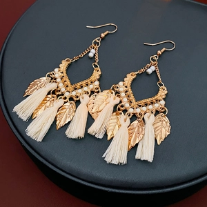 Detailed view of ethnic leaf-shaped earrings with gold metal and beige fringe tassels
