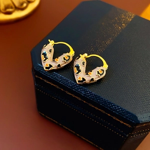 Macro view of heart-shaped leopard print enamel earrings with golden metal edges on a blue box