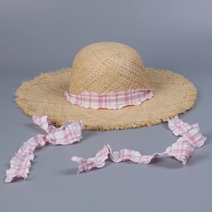 Detail of raffia sun hat with pink gingham ribbon tie and frayed straw brim