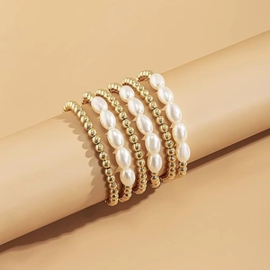 Close-up of stacked gold beads and pearl bracelets on a cylinder display stand
