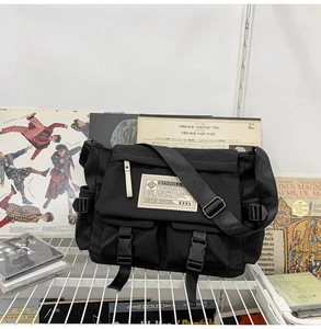 Detailed view of black nylon messenger bag with multiple pockets and adjustable shoulder strap