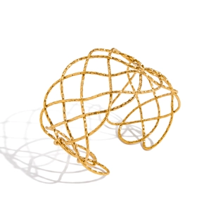 Macro detail of 18K gold-plated hammered texture on irregular cutout bangle bracelet