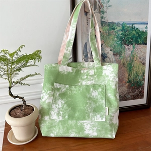 Dettaglio della borsa tote in tela tie-dye verde con tasca frontale ed etichetta tessuta