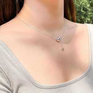Detail of silver snake bone necklace with Y-shaped pendant featuring polished metal beads