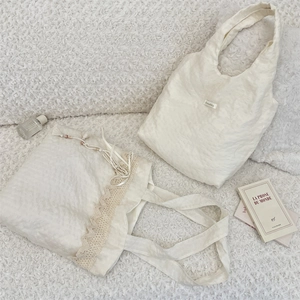 Detail of cream canvas tote bags with delicate lace trim and ribbon bow on plush background