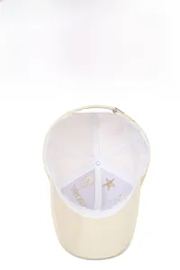 Detail of breathable inner lining and gold star embroidery on a cream baseball cap