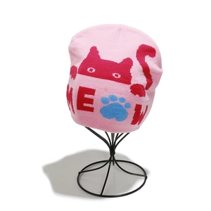 Detail of pink knitted beanie featuring a red cat pattern and Meow text on mesh stand