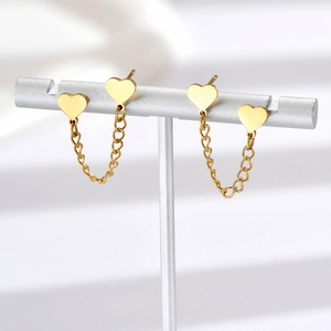Detail of golden heart-shaped chain earrings displayed on a professional jewelry stand