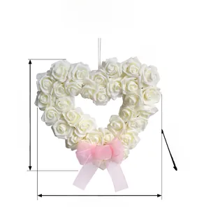 Détail d'une couronne de roses blanches en cœur avec nœud en organza rose et dimensions