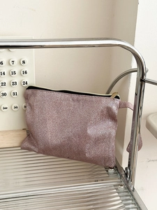 Close-up of pink glitter cosmetic bag with snakeskin texture on a silver metal shelf