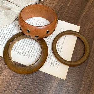 Detail of retro wooden texture bangles set with metal studs on vintage paper