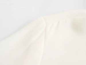 Detail of fine shoulder stitching on a cream white elegant chiffon blouse fabric