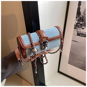Detailed shot of cylinder denim crossbody bag with M letter logo and chain strap