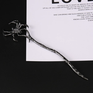 Macro shot of gothic spider skull hair pin with textured gunmetal finish on a card