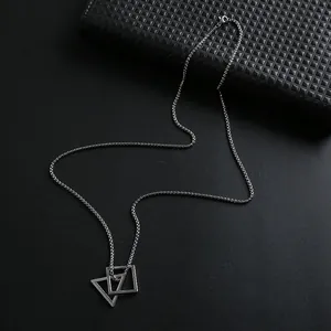 Close-up of geometric square and triangle interlocking pendants on wheat chain necklace
