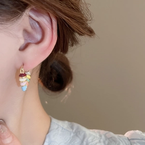 Detail of colorful enamel hoop earrings with vibrant stacked rings on a golden base
