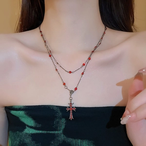 Close-up of double-layer vintage necklace with red crystals and gothic cross pendant