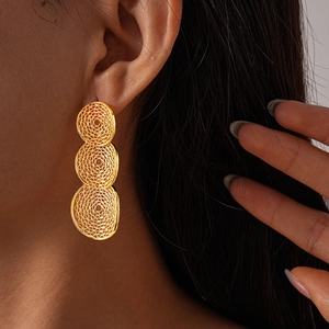 Close-up of gold hollow mesh geometric round drop earrings worn by a model