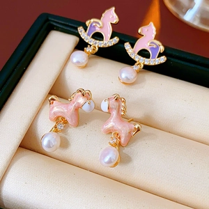 Detailed view of rocking horse pearl earrings with pink zircon accents in a jewelry box