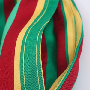 Macro view showing reinforced pocket stitching on multi-colored striped woven trousers