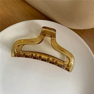 Macro detail of the large amber transparent acrylic hair claw clip on a white plate